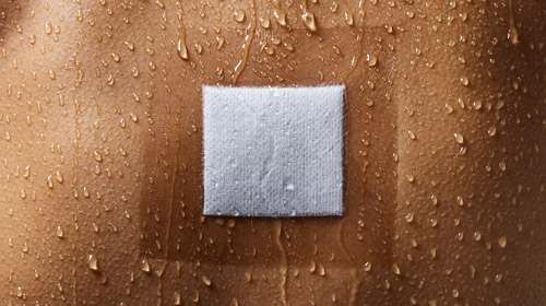 Close-up of a Hypafix transparent dressing fixating a gauze on wet skin with droplets and image showing Hypafix transparent benefits: best adhesive force, high MVTR rate, highest stretchability. Close-up of a Hypafix transparent dressing fixating a gauze on wet skin with droplets and image showing Hypafix transparent benefits: best adhesive force, high MVTR rate, highest stretchability.